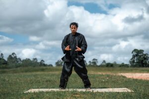 A man standing in an open field practicing qigong.