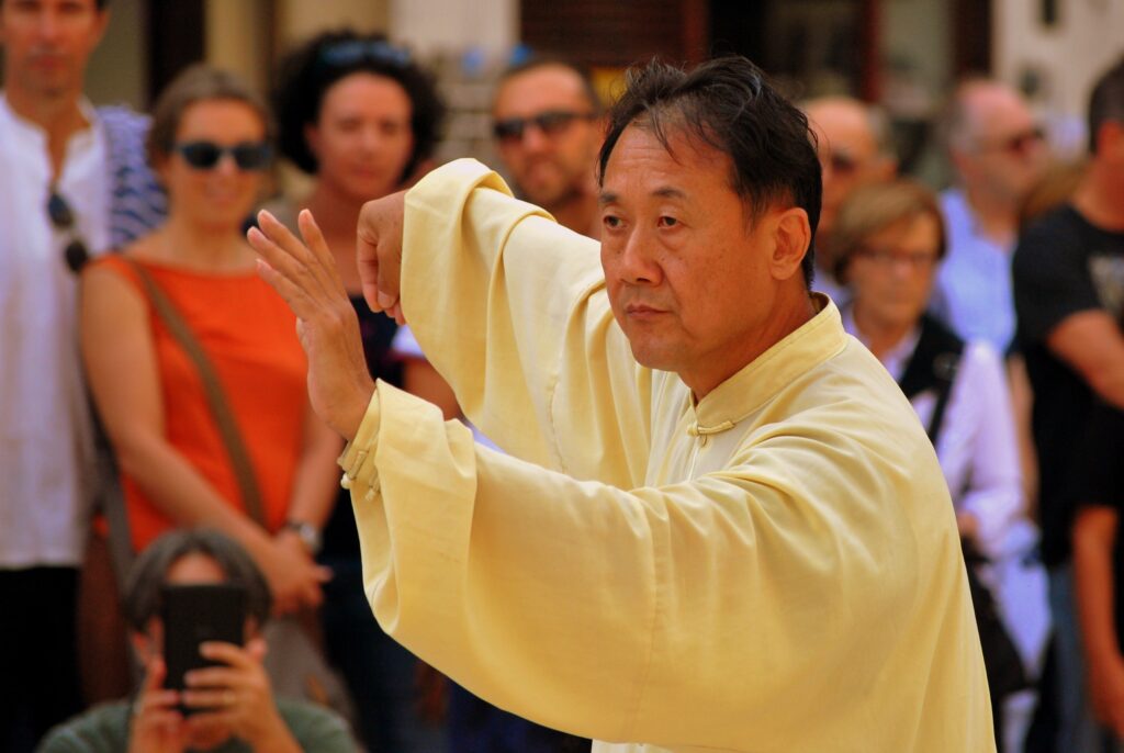 A middle-aged man practicing tai chi in public