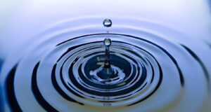 Blue water droplet creating gentle ripples.